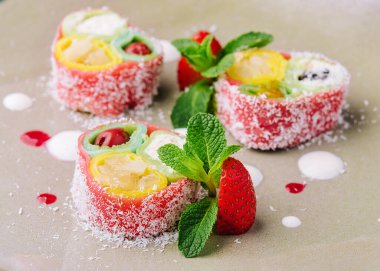 rolls of pink pancakes with different fruits and berries