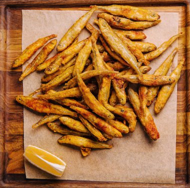 wooden board of fried whitebait with slices of lemon