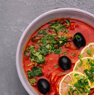 red soup Solyanka, with sausage, olives and lemon