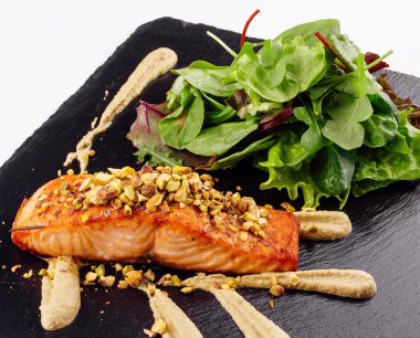 Grilled salmon fish fillet with crushed pistachios with green salad