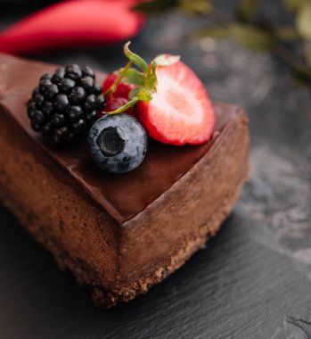 Tahta masada taze böğürtlenlerle süslenmiş lezzetli çikolatalı pasta.