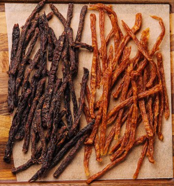 Beef and chiken jerky on wooden board