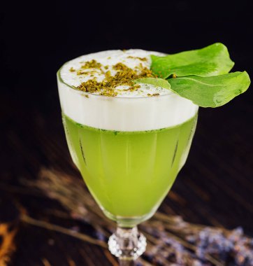Fresh basil sour cocktail with white foam with green basil leaf in a glass