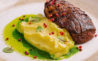 Mashed potatoes and beef steak with pesto sauce