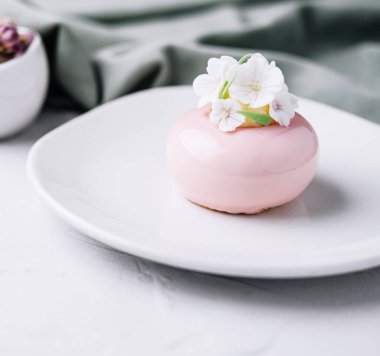 Pink mousse cake decorated with white flowers