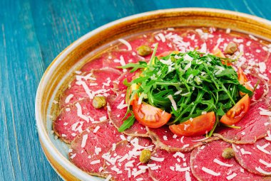 Beef carpaccio with capers, parmesan, arugula and tomatoes