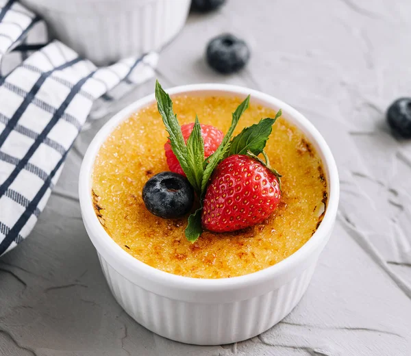 cup of creme brulee with dessert plug and mint leave with berries