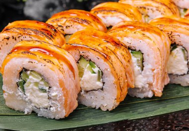 Rolls with fried salmon and cheese, cucumber on plate