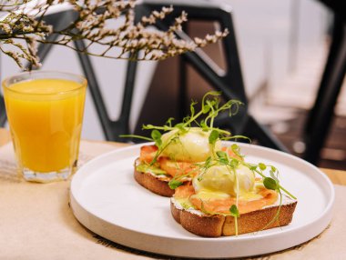 Bread Toast with smashed Avocado, Salmon and Poached Egg and orange juice