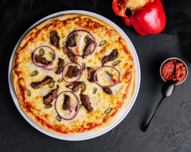 italian pizza with tomatoes, cheese, onions on black