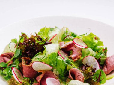 Roast beef salad with green mix on plate