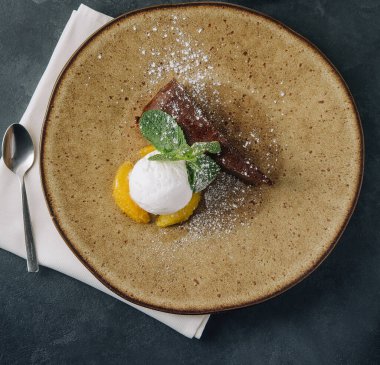 Chocolate brownie with ice cream and vanilla powder on plate