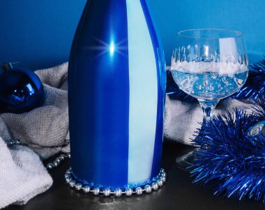 Mavi arka planda bir şişe şampanya ve Noel oyuncakları