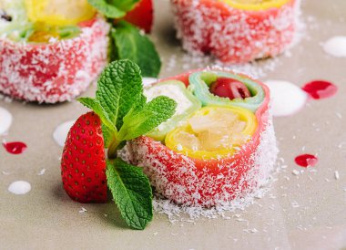 rolls of pink pancakes with different fruits and berries