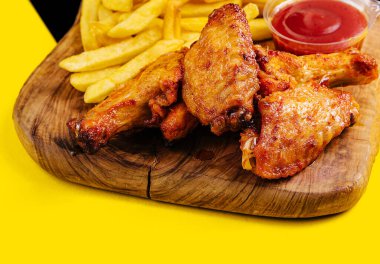 Breaded crispy fried chicken wings, french fries and sauce