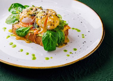bread toast with avocado, poached egg, salmon and basil leaves