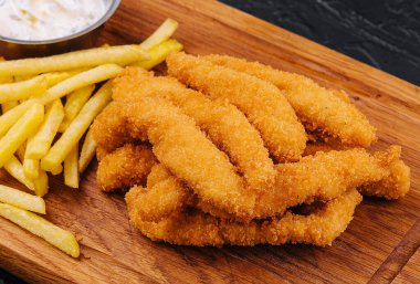 chicken nuggets and french fries on wooden board