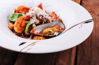 siyah beyaz tabakta su ürünleri spagetti