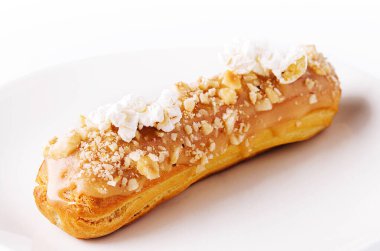 Caramel eclair on white plate isolated