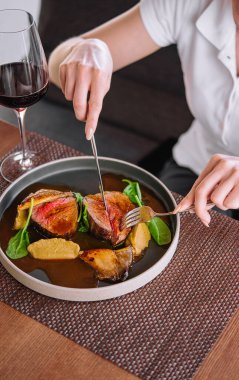 Kadın elleri çatal ve bıçakla kavrulmuş ördeği şarapla keser.