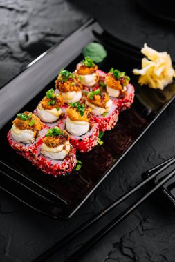 Japon yemeği. Siyah tabakta suşi yuvarlanıyor.
