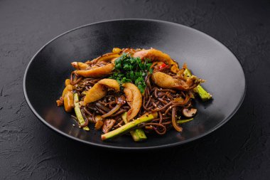 Çin usulü kızarmış karabuğday makarnası ve siyah tabakta et.