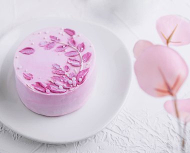 Pembe kremalı ve çiçekli bir parça çikolatalı pasta.