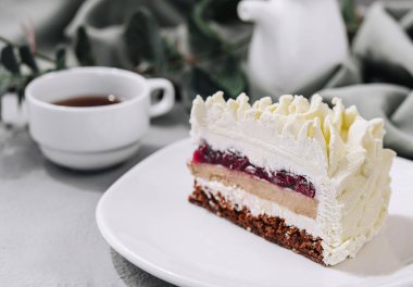 Beyaz tabakta kremalı pasta ve bir fincan çay.