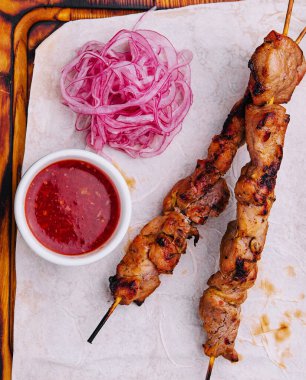 Tahta bir şiş ve kırmızı soğanlı domuz kebabı.