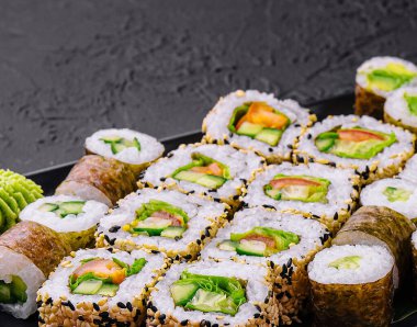 Vejetaryen suşi siyah tabakta yuvarlanıyor.