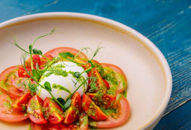 Tabakta servis edilen Burrata peyniri ve domates salatası.