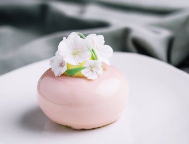 Pink mousse cake decorated with white flowers
