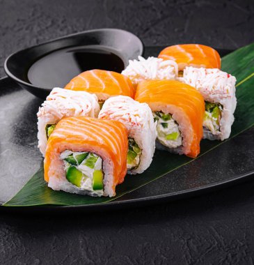 Somon balıklı suşi ve siyah tabakta yengeç.