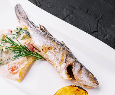 Brokolili balık ve beyaz tabakta sos.