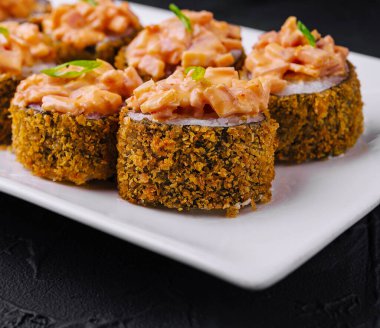 Beyaz tabakta kızarmış suşi rulosu.