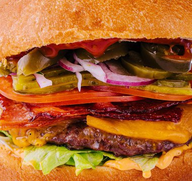Sığır etli, domatesli, peynirli, pastırmalı ve marullu hamburger.