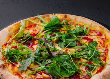 Kara tahtada roka olan pizza.