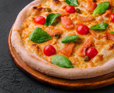 Domatesli, peynirli, somonlu ve fesleğenli lezzetli deniz ürünleri pizzası.