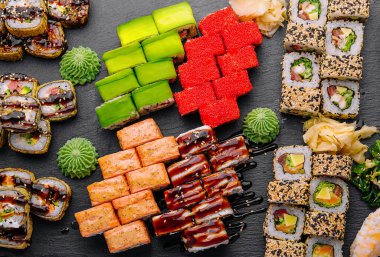 Büyük suşi seti, siyah arka planda tepeden çekilmiş.