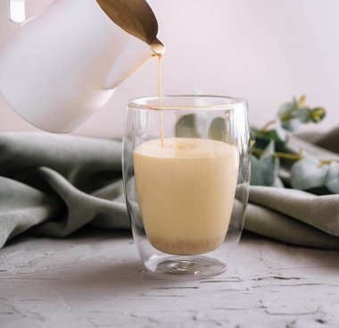 Çaydanlıktan cam fincana sütlü kahve dolduruyorum.