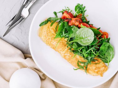 Omelet with arugula, tomatoes and basil in a plate