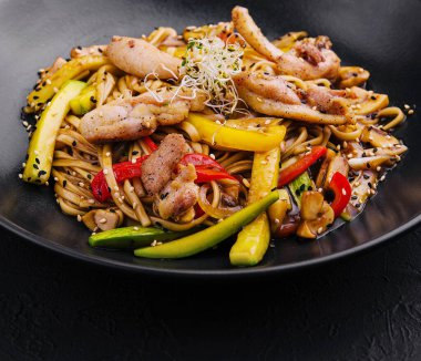 Siyah tabakta sebzeli Çin pilavı.