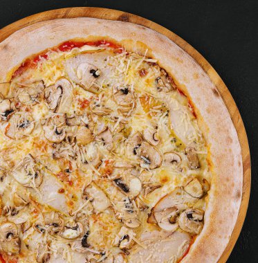 Pizza with ham and mushrooms on a wooden board