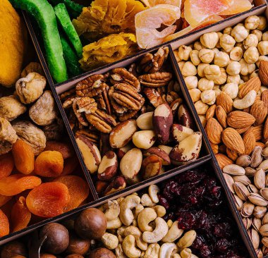 Tahta bir kutuda çeşitli fındıklar ve kurutulmuş tropik meyveler.