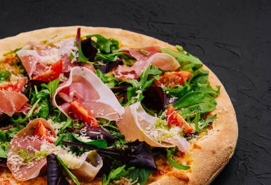 Prosciutto, roka ve parmesanlı pizza.