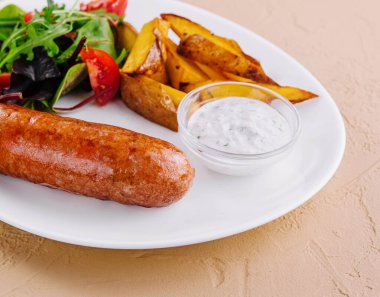 Kızarmış sosis, fırında patates ve yeşil salata.