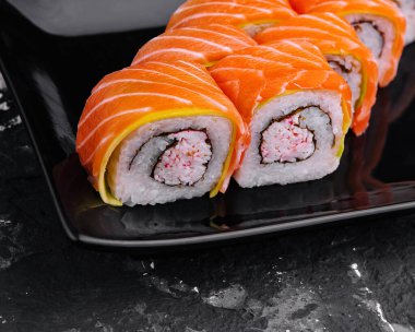 sushi rolls with salmon and crab on black plate clipart
