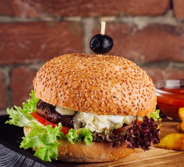 American cheeseburger with French fries on wooden board