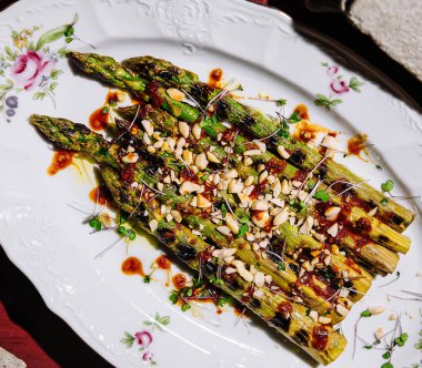 Baked asparagus with pine nuts on plate clipart