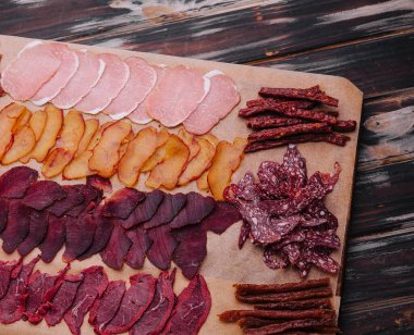 Bir tahtanın üzerinde çeşitli kurutulmuş et ve sosisler.